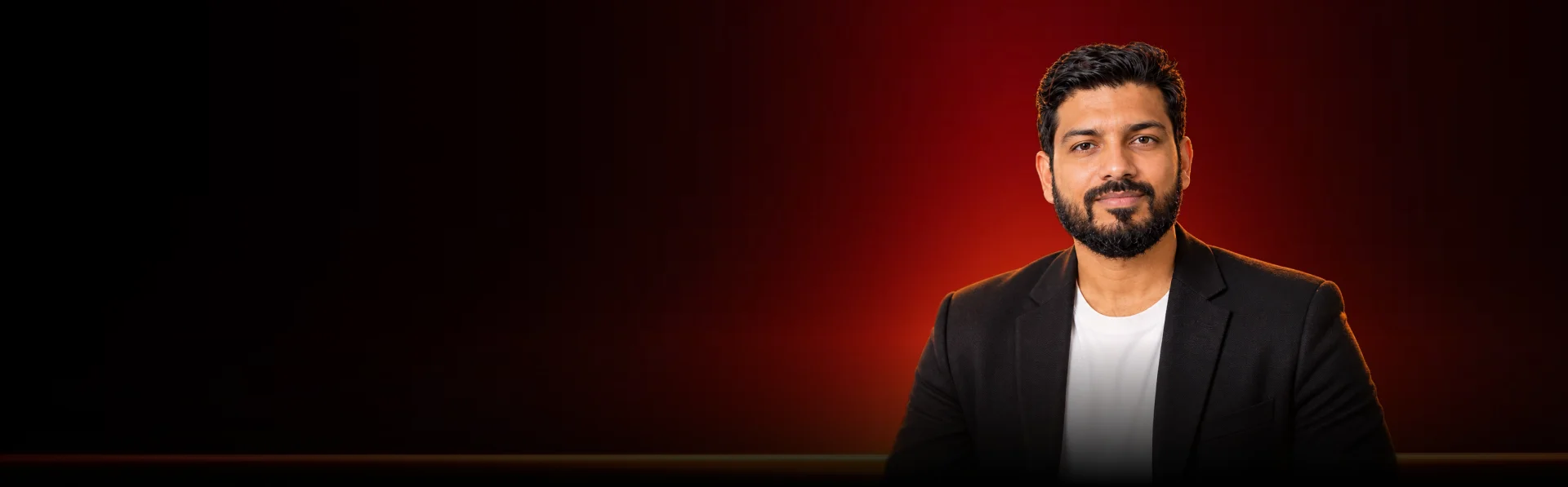 Professional in a black blazer against a dark background with red accent lighting