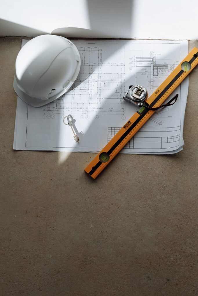 Construction blueprint with a safety helmet, measuring tools, and site planning equipment.