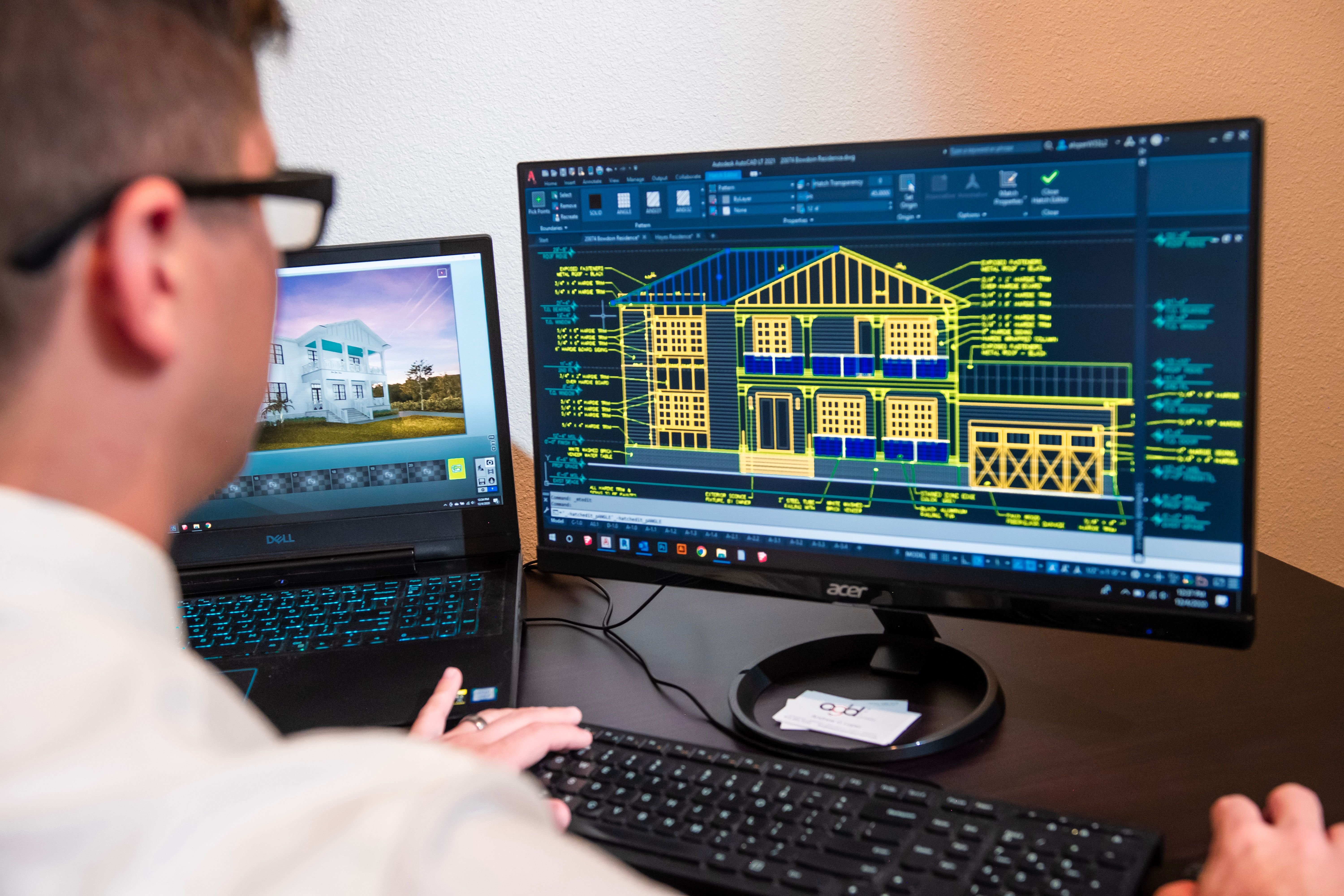 CAD technician designing a residential building in AutoCAD, viewing architectural elevations and technical drafting details on a desktop monitor.