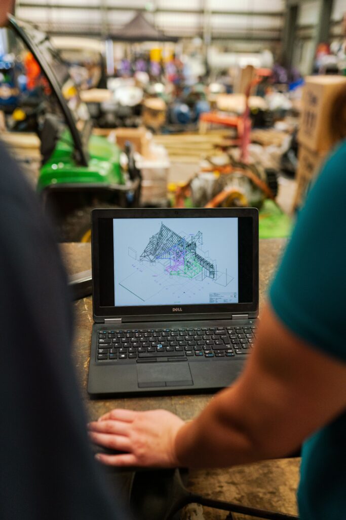 Engineers collaborating on a CAD model displayed on a laptop during a construction and design project review.