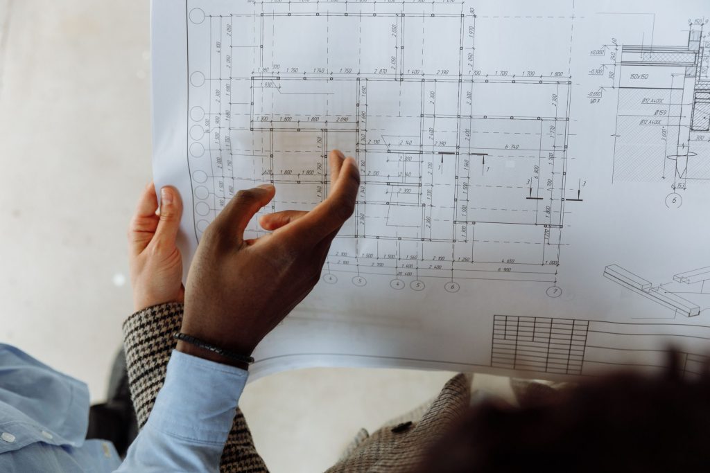 Construction professionals examining technical drawings and blueprint plans during a project coordination meeting.