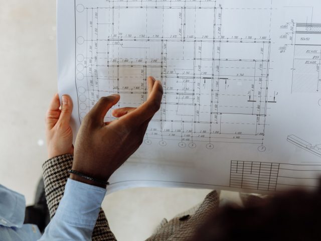 Construction professionals examining technical drawings and blueprint plans during a project coordination meeting.