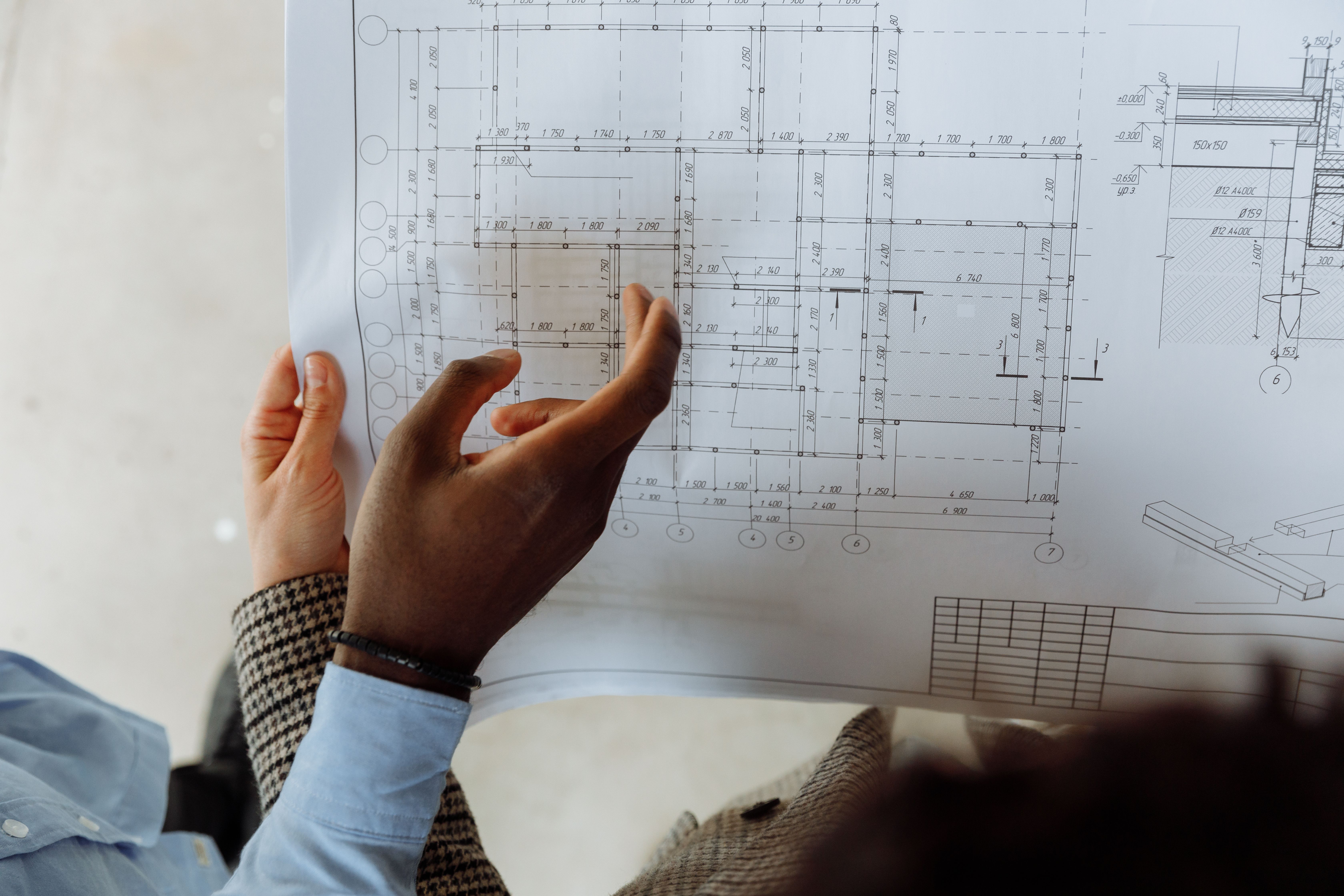 Construction professionals examining technical drawings and blueprint plans during a project coordination meeting.