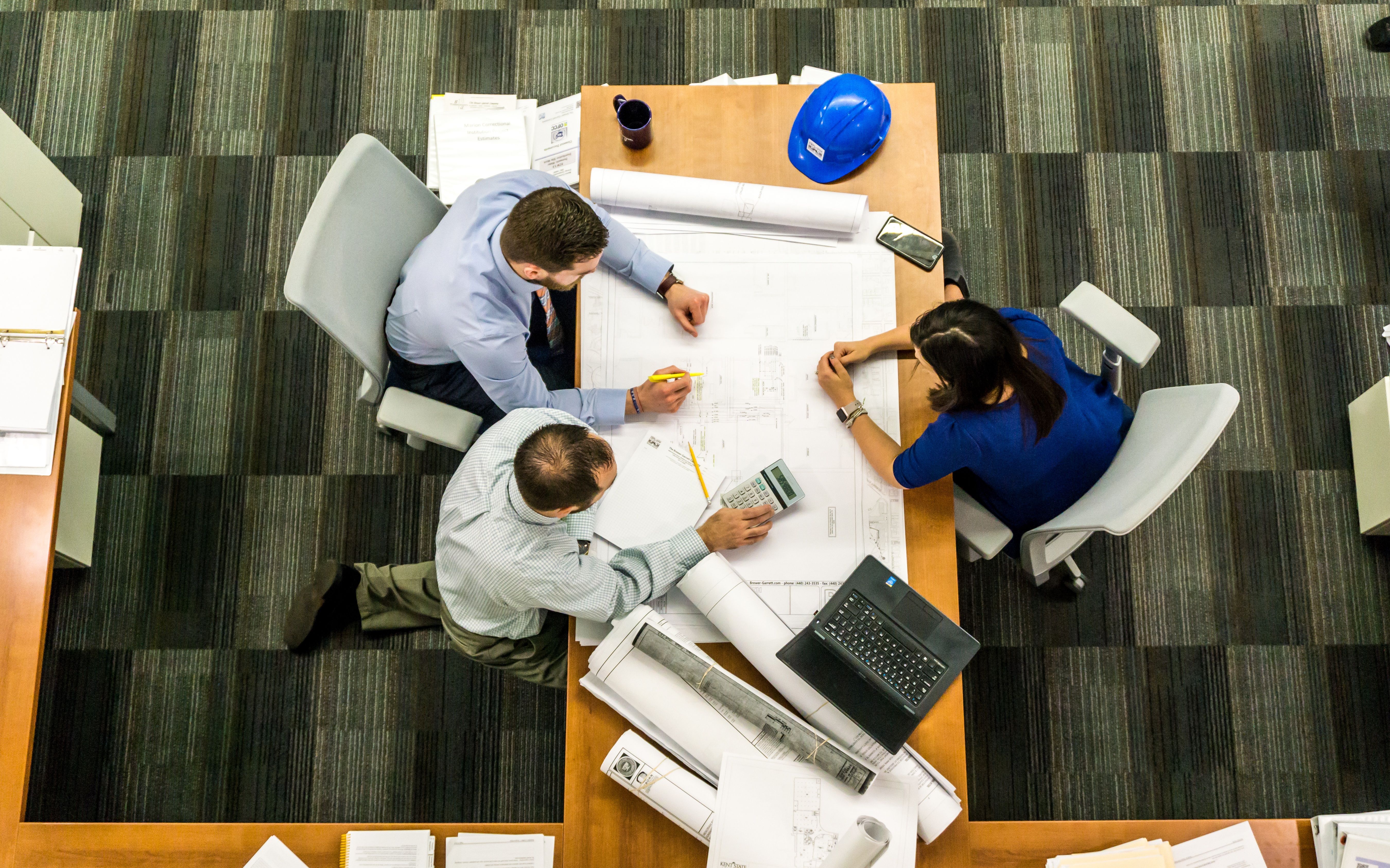 Civil engineering team reviewing construction drawings and project plans around a conference table.