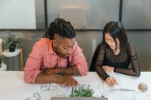 Project team members discussing floor plans and project details during an architecture, engineering, and construction coordination meeting.