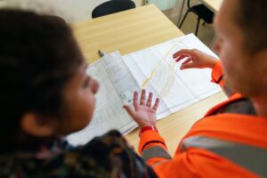 Construction professionals reviewing engineering drawings and site plans during a project coordination meeting.
