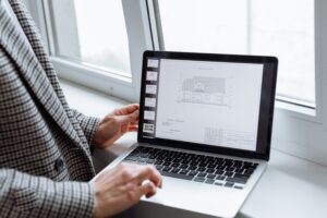 Construction drafting professional reviewing CAD drawings and building plans on a laptop
