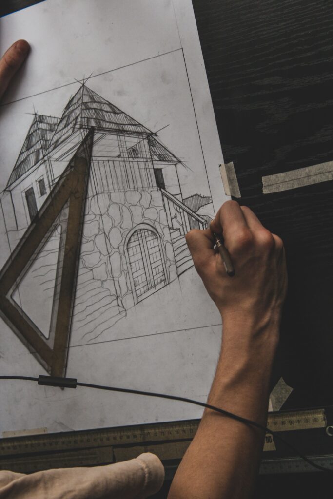 Architectural drafter creating a detailed building sketch by hand using drafting tools and technical drawings.
