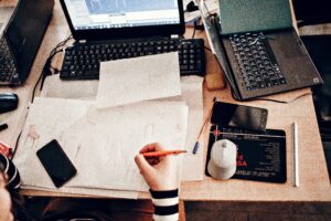 CAD Back Office Support professional reviewing technical drawings and drafting documents at a workstation