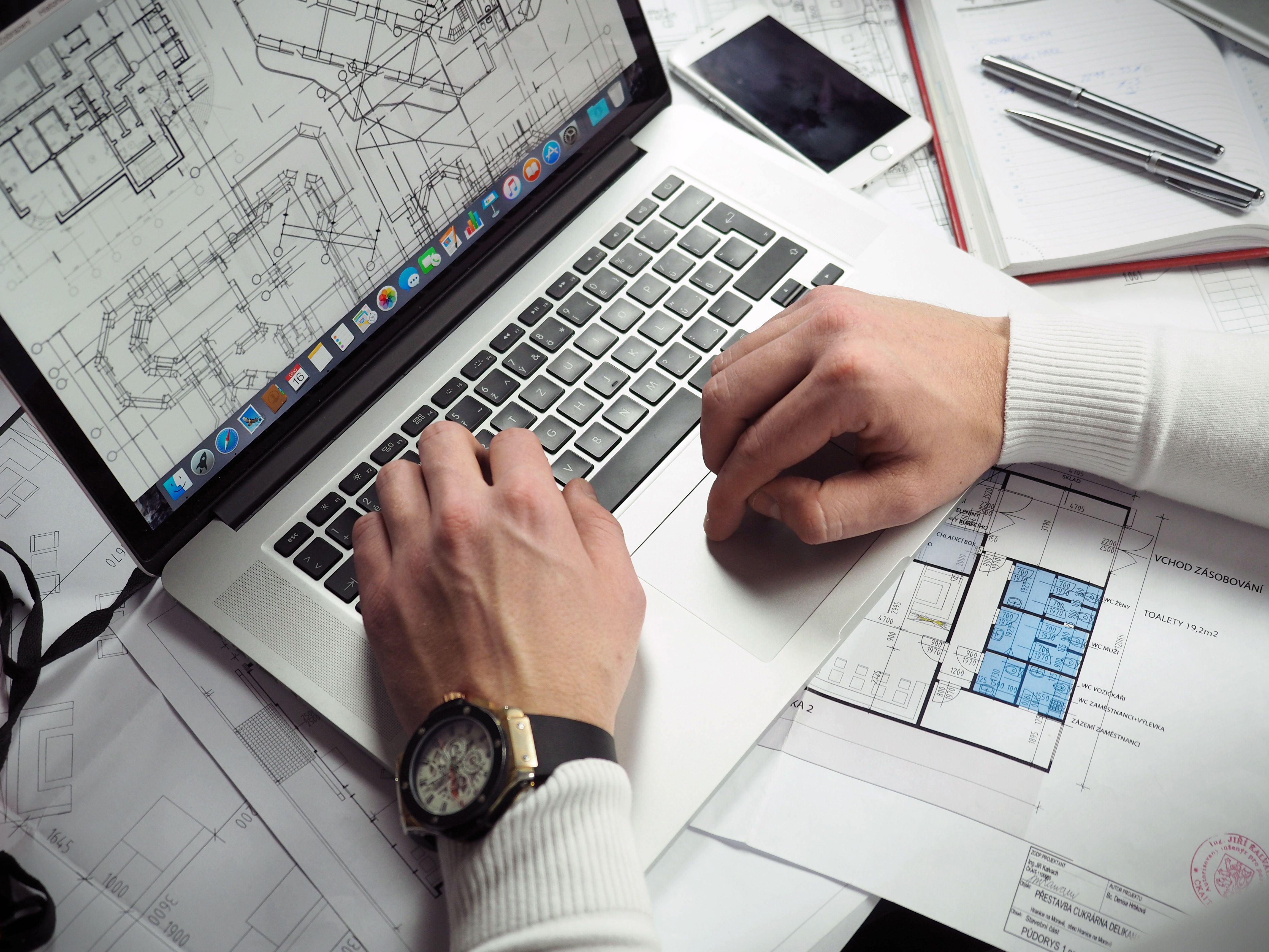 CAD professional using a laptop to review and edit technical building drawings and construction plans.