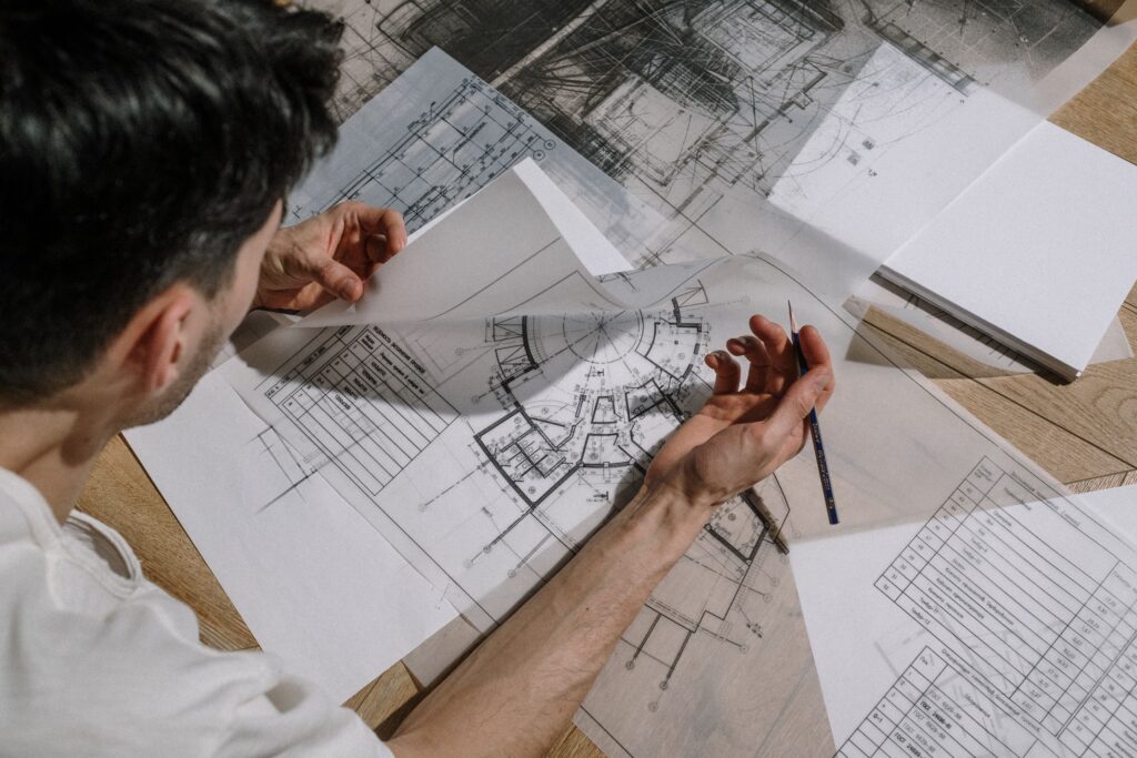 Architect reviewing construction drawings and architectural blueprints on a desk during project planning and design coordination.