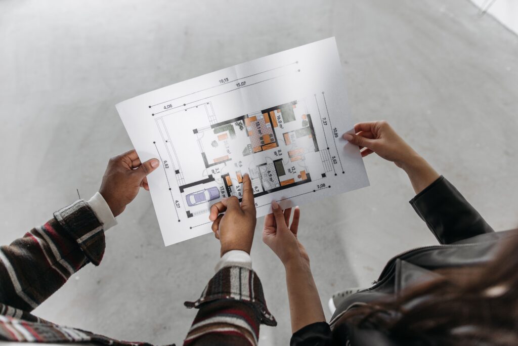 CAD drafter reviewing and discussing a residential floor plan drawing during project planning.