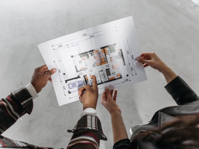 CAD drafter reviewing and discussing a residential floor plan drawing during project planning.
