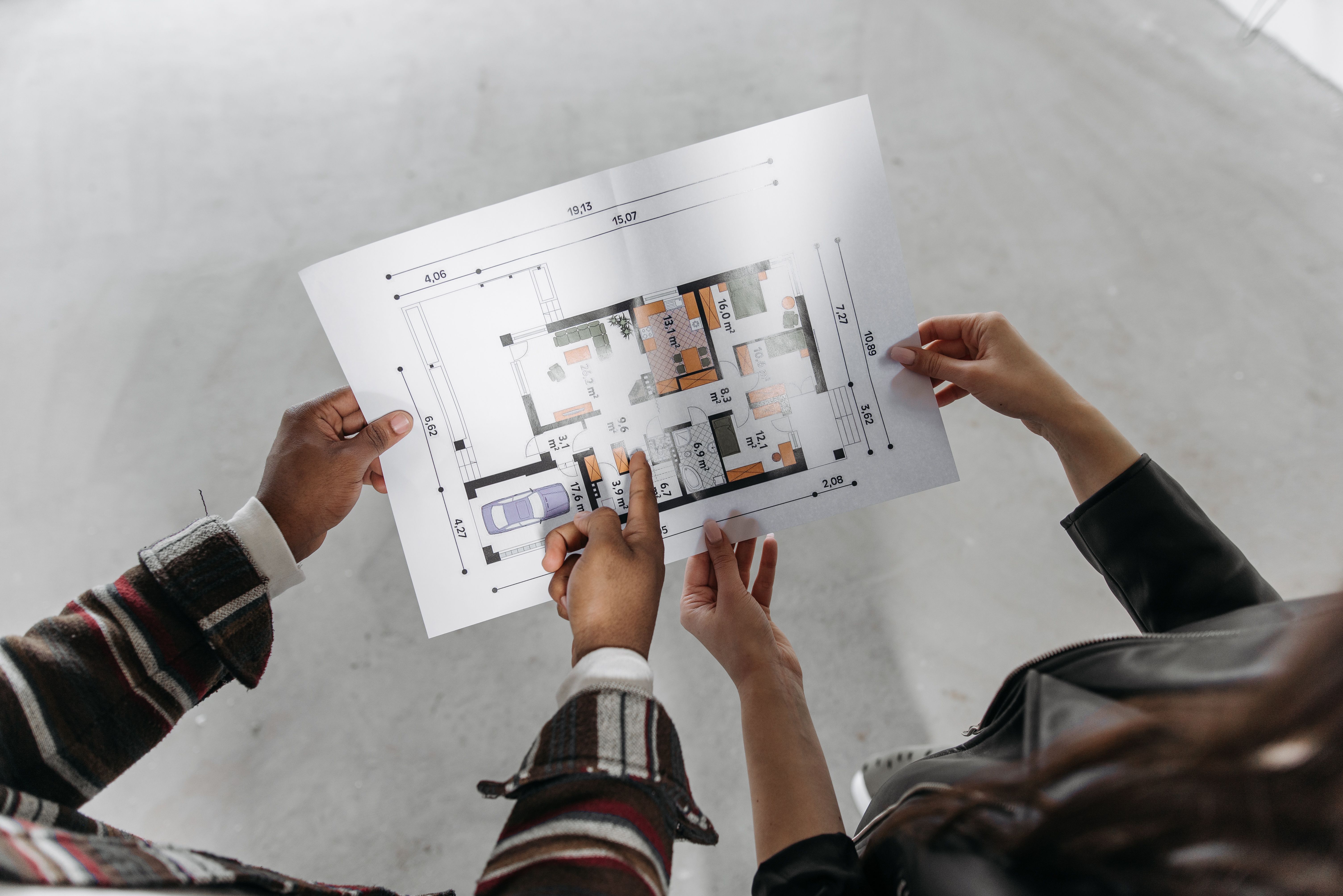 CAD drafter reviewing and discussing a residential floor plan drawing during project planning.