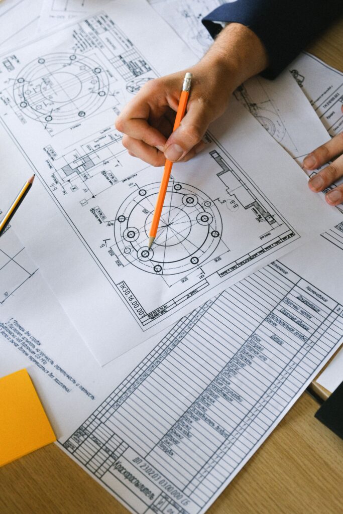 CAD drafter marking technical drawing revisions and dimensions on engineering plans.