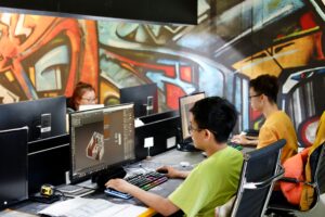 Construction design team working on CAD and 3D modeling projects at computer workstations in a modern office.