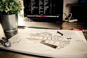 Architectural concept sketch on a desk beside a laptop, representing design planning and project development.