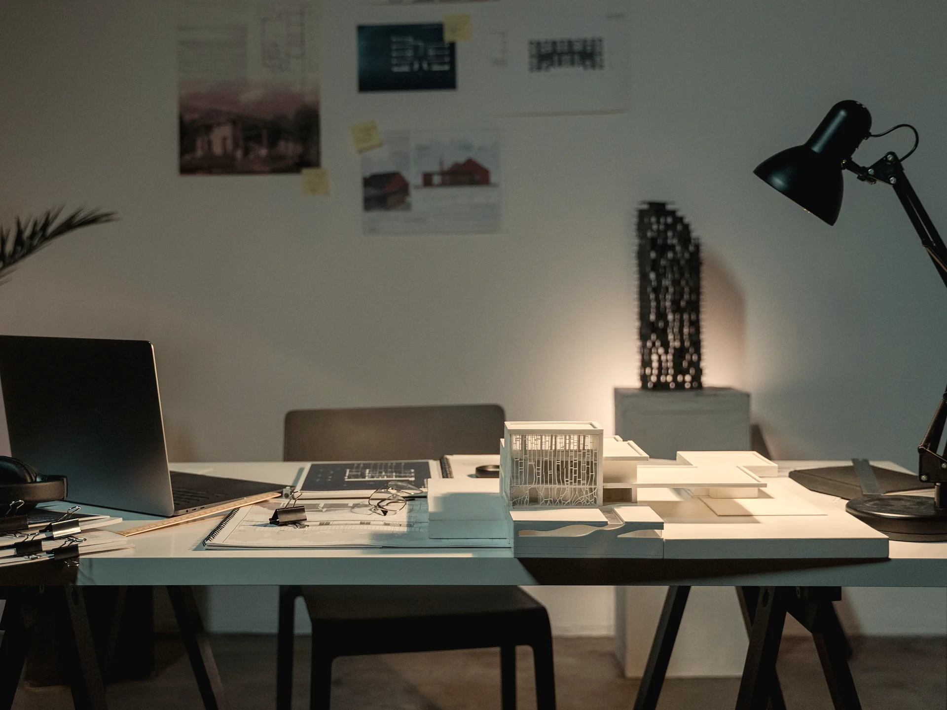 Architect's desk with building models, drawings, and a desk lamp