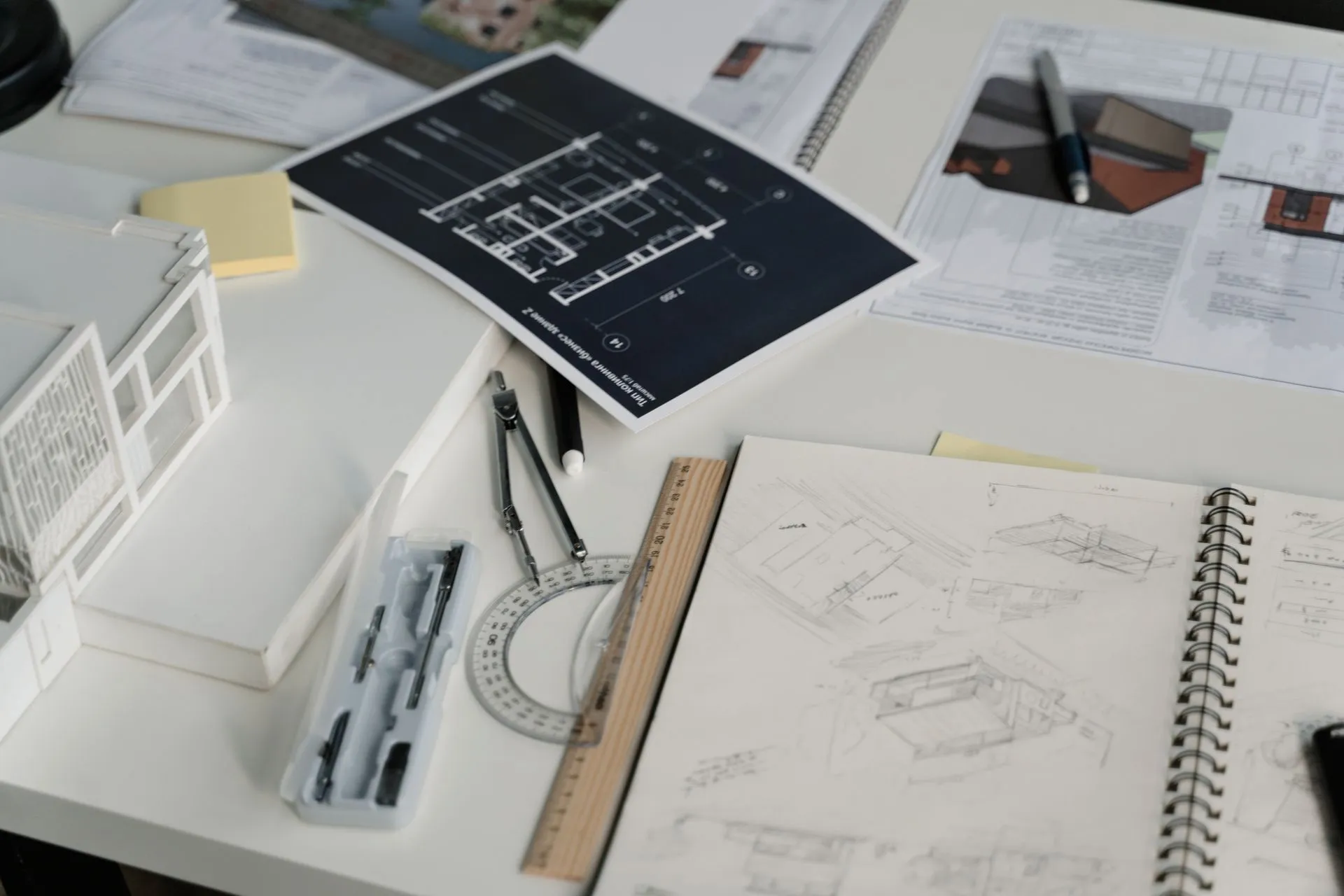 Construction drawings, sketches, ruler, and drafting tools spread across an office desk