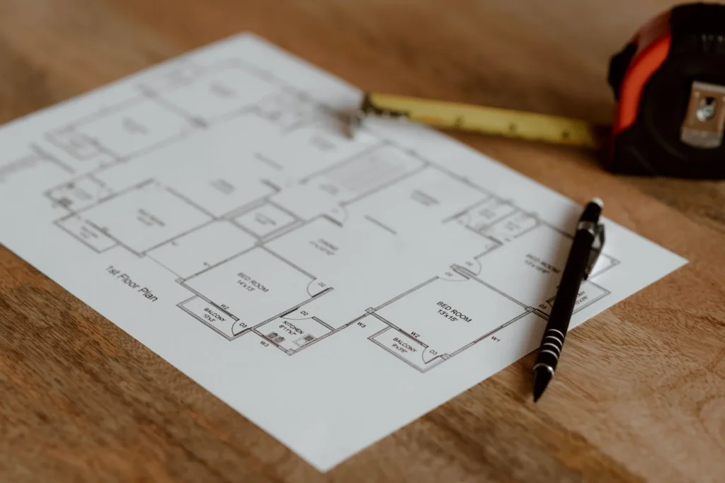 Printed floor plan on a wooden desk with a pen and tape measure, ready for a quantity takeoff