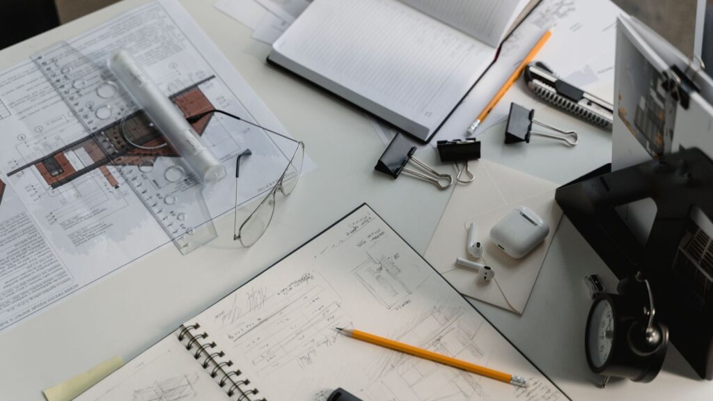 Outsourced construction estimating workspace with architectural drawings, takeoff notes, pencil and drafting tools on a desk