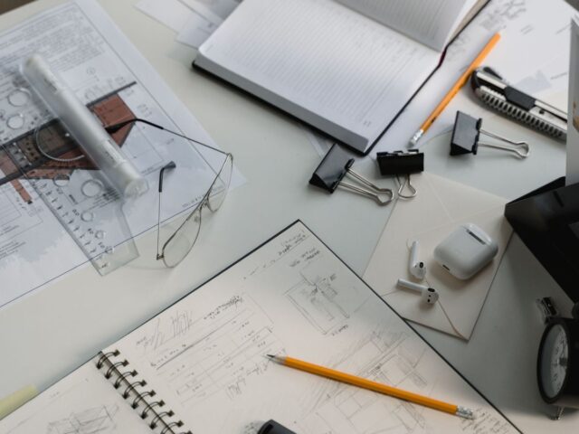Outsourced construction estimating workspace with architectural drawings, takeoff notes, pencil and drafting tools on a desk